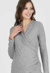 Graues Langarm-Oberteil mit Wickeldesign. Verfügt über gerippten Stoff und geraffte Details auf einer Seite, die eine taillierte Silhouette bietet.