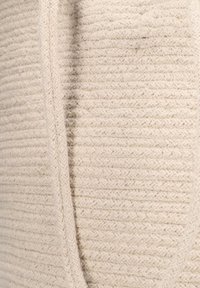 Beige breisel met een textuur en geribbelde structuur met horizontale lijnen en een naadloze rand. Zacht en knus uiterlijk met een warme tint.