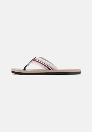 Tan flip-flop sandal featuring a woven strap with black and red accents, a cushioned beige footbed, and a black rubber sole.