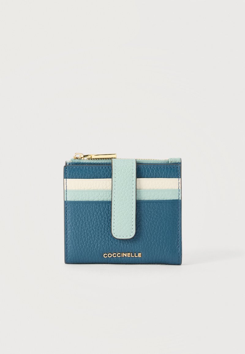 Συμπαγές δερμάτινο πορτοφόλι σε μπλε χρώμα με οριζόντιες ρίγες σε ανοιχτό μπλε και λευκό, χρυστό φερμουάρ και μπροστινό ιμάντα με κούμπωμα, με την επωνυμία Coccinelle.