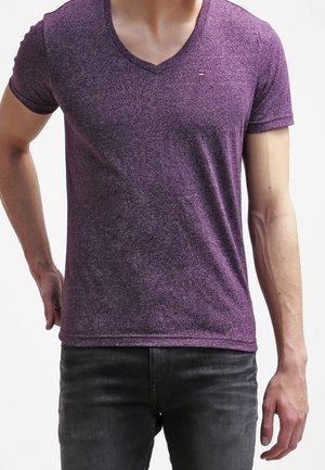 Lilla v-neck t-shirt med meleret effekt lavet af letvægtsstof; korte ærmer og en lille logoaccent på brystet. Kombineret med mørke jeans.