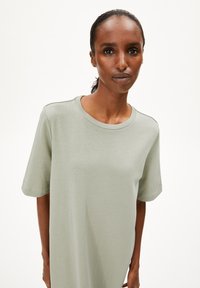 Hellgrünes Baumwoll-T-Shirt mit Rundhalsausschnitt und kurzen Ärmeln. Weicher Stoff, lockere Passform und nahtloses Schulterdesign.