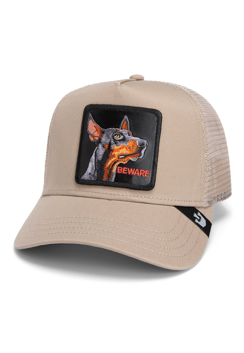 Gorra beige con malla en la parte posterior; presenta un parche cuadrado negro con un perro bordado y el texto "CUIDADO" en rojo. Visera estructurada con detalles de costura.