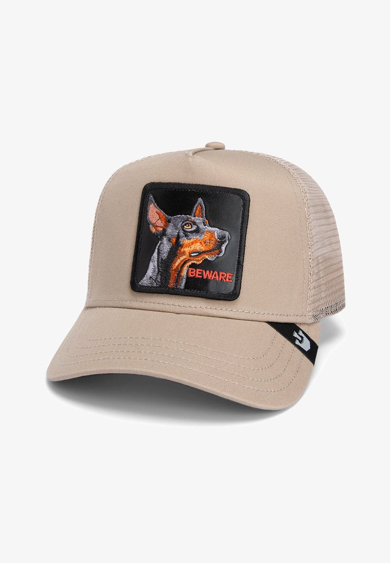 Gorra beige con malla en la parte posterior; presenta un parche cuadrado negro con un perro bordado y el texto "CUIDADO" en rojo. Visera estructurada con detalles de costura.