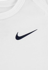 Tricou alb din bumbac cu logo-ul negru Nike Swoosh. Designul include un gât rotund și mâneci scurte, cu o textură netedă.
