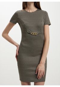Robe ajustée à motifs noirs et dorés avec manches courtes, encolure ronde et un accent chaîne dorée à la taille. Texture lisse, longueur au genou.