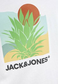 Camiseta de algodón blanca con un gráfico de una piña verde y un sol marrón sobre un fondo en tonos pastel. Texto negro "JACK & JONES" en la parte inferior.