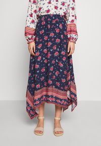 Jupe longue fleurie bleu marine avec des roses rouges, présentant un ourlet à motifs et une ceinture élastique. Tissu léger pour le confort et la fluidité.