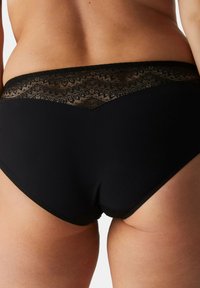 Schwarze Unterwäsche mit Spitzendekoration auf der Rückseite, ausgestattet mit einem glatten Bund und weichem Material, entworfen für Komfort und Passform.