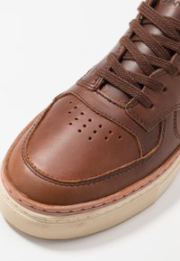 Brune læder sneakers med rund tå, struktureret overflade, tone-i-tone snørebånd, perforeret detalje på tåboksen og cremet gummisål.