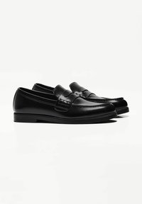 Black leather loafers with a smooth texture, featuring a strap accent and stitched detailing, resting on a low black sole.