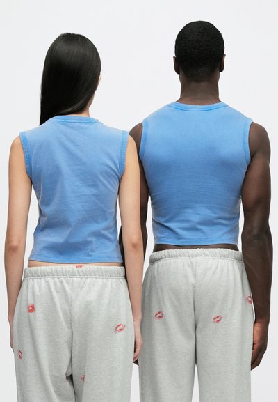 Top cropped azul feitos de algodão, com design sem mangas e gola redonda. Combinados com calças de fato de treino cinzentas adornadas com estampas de lábios.
