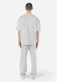Hellgraues, oversized T-Shirt mit kurzen Ärmeln und Rundhalsausschnitt, kombiniert mit passenden, lockeren Hosen, gefertigt aus weichem Stoff.