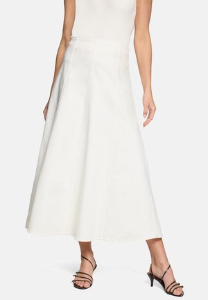 Jupe midi blanche taille haute en A, portée avec un top blanc sans manches côtelé et des sandales noires à talons bas et fines brides.