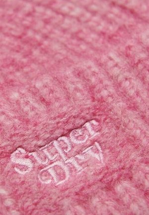 Tissu rose doux et texturé avec le logo blanc brodé "Super Dry" centré dans le cadre.
