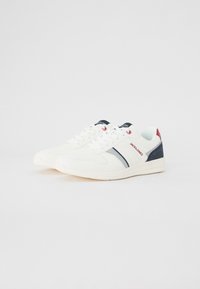 White sneakers with navy and red accents. Featuring a smooth material, laced closure, and a patterned textile panel on the heel.