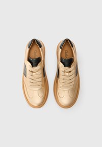 Sneakers in pelle dorata con accenti neri, punta rotonda, lacci piatti e suola in gomma beige. Texture liscia e design minimalista.