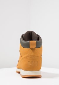 Bruine en oranje wandelschoen met een gevoerde kraag, gestructureerde bovenkant, logo-detail op de hak en een duurzame rubberen buitenzool.
