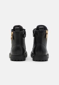 Černé kožené kotníkové boty s texturovaným povrchem, vybavené bočním zipem, pevnou podrážkou a nízkým podpatkem pro stabilitu.