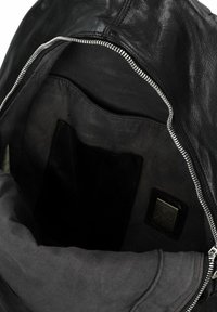 Interno di una borsa in pelle nera con texture liscia, che mostra una chiusura con cerniera e una tasca singola lungo il lato.