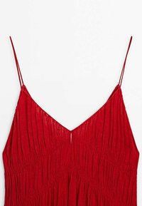 Punainen ilman hihoja oleva mekko, jossa on V-pääkallo ja taitettu rakenne. Ominaisuudet ohuet hihnat ja halkio takasuunnassa. Silkkinen kangaspinta.