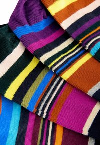 Calzini colorati a righe con diversi motivi in tonalità di viola, blu, giallo e verde, con righe di larghezze variabili.