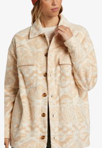 Fleece shirt jacket in roomwit en beige, met een spiraalpatroon, knoopsluitingen en twee borstzakken met een relaxte pasvorm.