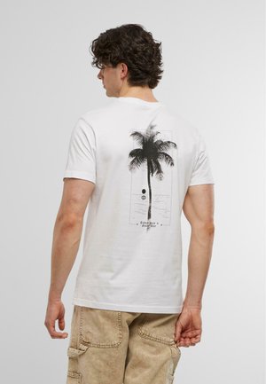 Weißes Baumwoll-T-Shirt mit einem schwarzen Palmen-Design auf der Rückseite. Das Design enthält einen Sonnenuntergang und Text am unteren Rand. Lässige Passform.