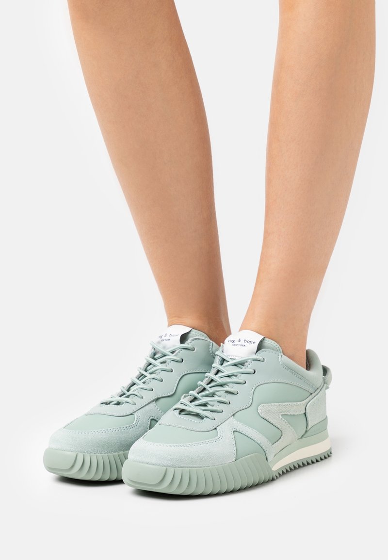 Zapatillas de cuero y ante verde claro con suela texturizada, con diseño de cordones y etiqueta de logo en la lengüeta. Forma de punta redondeada.