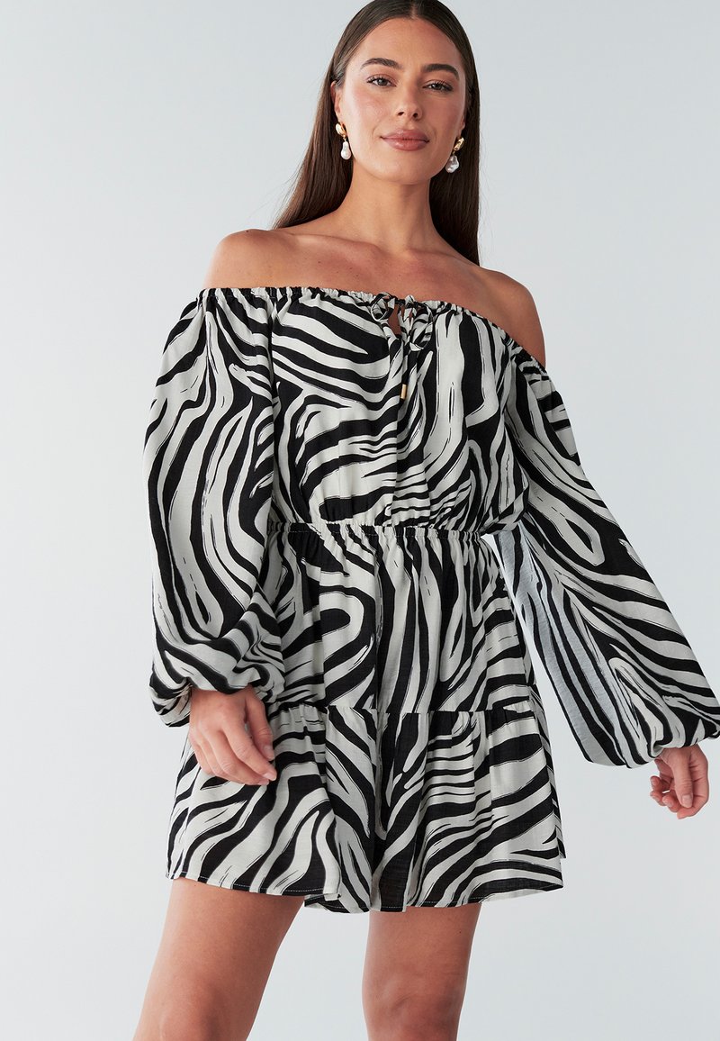 Sukienka odsłaniająca ramiona z czarno-białymi paskami zebry, marszczonym pasem, warstwową spódnicą i długimi, luźnymi rękawami. Lekka tkanina.