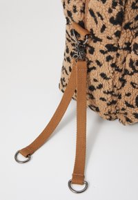 Bolsa com padrão de leopardo em tecido texturizado em tom beige, com uma alça castanha. Possui um clipe de metal prateado e detalhes em metal para fecho.