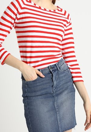 Rød- og hvidstribet langærmet top parret med en højlivet denimskørt. Skørtet har en flosset kant og klassisk fem-lomme design.