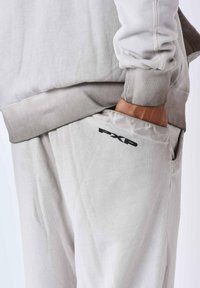 Lichtgrijze sweatshirt en bijpassende joggers met ribgebreide manchetten, voorzien van een zijzak en een zwart "PXP" logo voor branding.