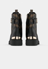 Bottines noires avec un talon sophistiqué agrémenté d'or, présentant un dessus texturé noir et marron à motifs et un détail de boucle sur le côté.
