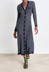 Námořnické pruhované midi šaty s výstřihem do V, dlouhými rukávy, předním zapínáním na knoflíky a dvěma hrudními kapsami; doplněné zlatými knoflíky a žebrovanými manžetami.