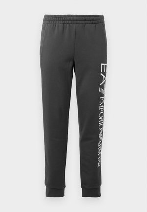 Pantalones de chándal grises con cintura elástica, piernas ajustadas y un estampado de logotipo blanco en el lado izquierdo. Textura de tela suave; sin bolsillos.