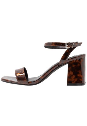 Sandalia de tacón alto en carey marrón con correa de tobillo ajustable, diseño de punta abierta y tacón cuadrado, con un acabado brillante.