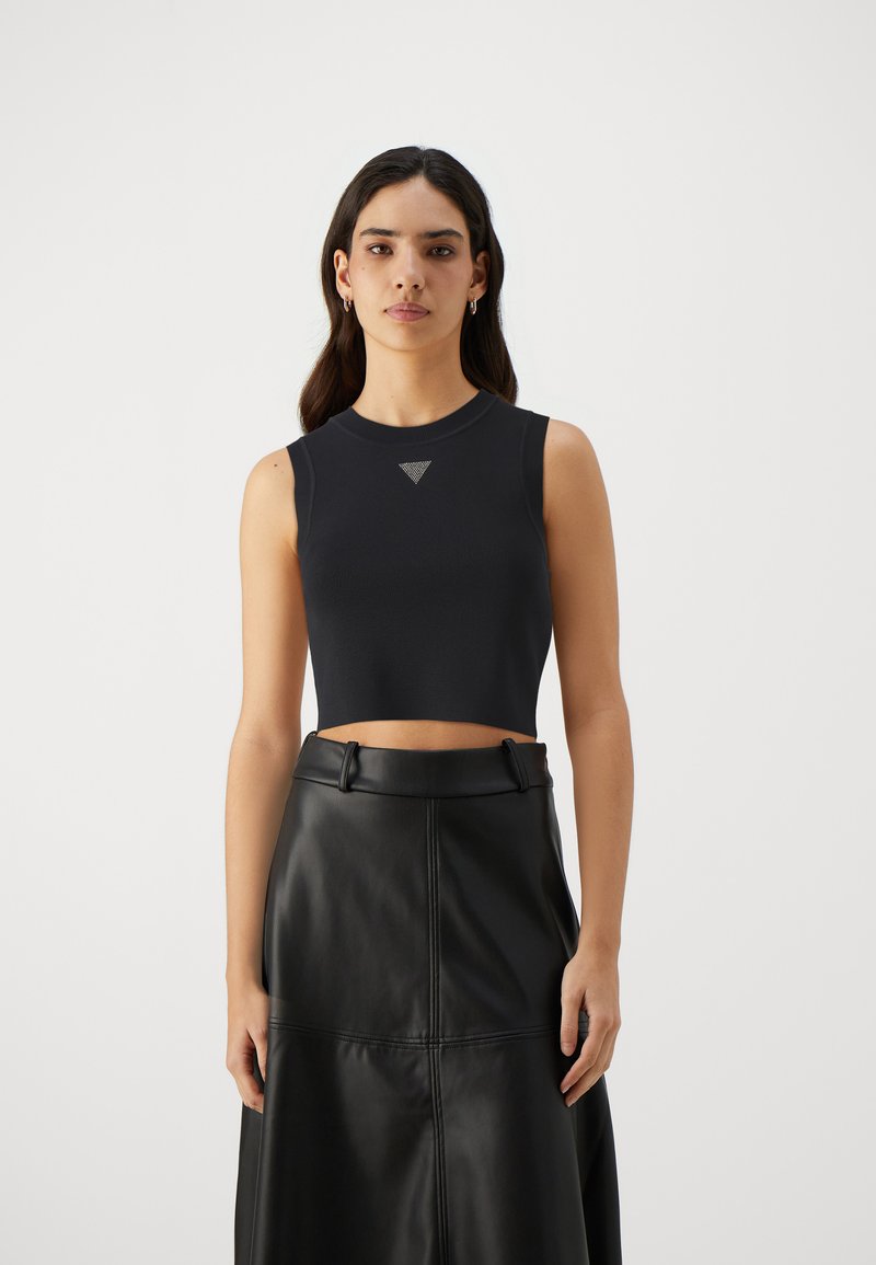 Black cropped sleeveless top in ribbed fabric featuring a small triangular logo on the chest, paired with a high-waisted black leather skirt.