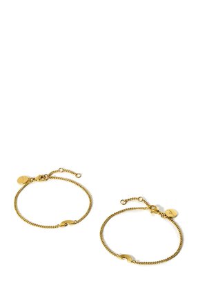 Zwei zarte goldene Kettenarmbänder mit kleinen regenbogenförmigen Anhängern und verstellbaren Verschlüssen auf weißem Hintergrund.