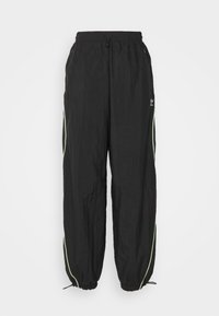 Pantalones de chándal negros de Adidas con cintura elástica, bolsillos laterales con cremallera, ribetes en verde neón a los lados y cordones ajustables en los puños.