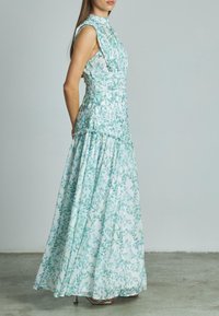 Ein ärmelloses, bodenlanges Kleid aus weißem Stoff mit einem helltürkisfarbenen Blumenmuster. Geraffter Oberteil und mehrlagiger Rock. Elegante Kragenverzierung.