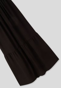 Abito nero, caratterizzato da un design a strati con una gonna fluida, realizzato in tessuto morbido, che mette in mostra una texture liscia e una lucentezza sottile.