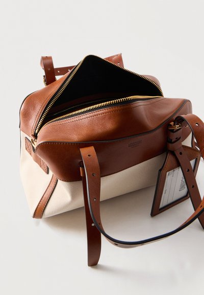 Τσάντα χειρός από καμβά και καφέ δέρμα με ανοιχτό χρυσό φερμουάρ, ρυθμιζόμενους δερμάτινους ιμάντες και προσαρτημένο ορθογώνιο θήκη κάρτας ταυτότητας.