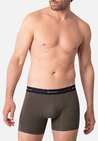 Boxers pour hommes en tissu vert olive foncé avec un design ajusté. Dotés d'une ceinture noire avec la marque "Eminence". Texture lisse.