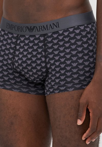 Boxer-briefs noirs avec un motif de logo gris répétitif, présentant une taille douce portant l'inscription "EMPORIO ARMANI" en noir. Texture de tissu lisse.
