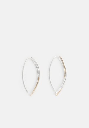 Delicate zilver- en goudkleurige gebogen oorringen met dunne draadhaakjes, afgebeeld tegen een effen witte achtergrond.