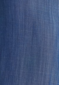 Tissu en denim bleu foncé avec une texture lisse, présentant un tissage diagonal subtil et de légères variations de teinte sur toute la surface.