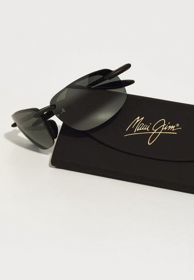 Sunglasses with dark gray lenses, black frames, and a case featuring gold "Maui Jim" branding. Sleek, wraparound design for a snug fit.