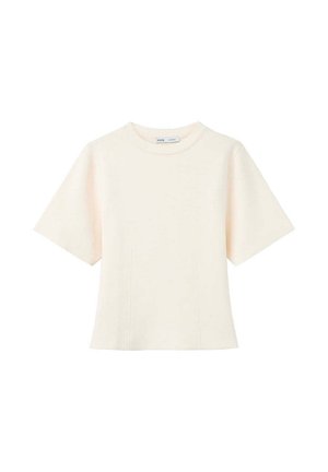 Top de mujer de manga corta color crema con cuello redondo y sutiles detalles de costuras verticales en la parte delantera.
