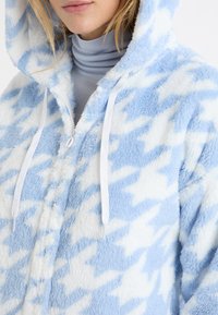 Bluza polarowa z kapturem w jasnoniebiesko-biały wzór pepitki, z zamkiem błyskawicznym z przodu, dwoma białymi sznurkami oraz miękką, teksturowaną tkaniną.